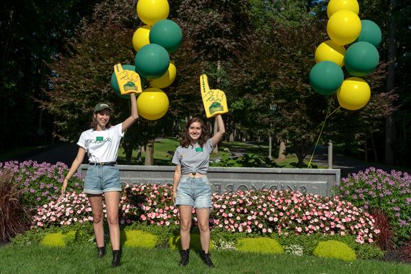 Two student stand by the Skidmore welcome sign 